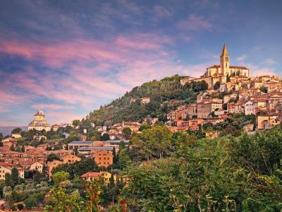 Hilltop cityscape at sunset with prominent church.