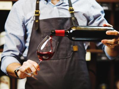 Sommelier pours red wine into a glass.