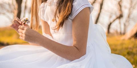 Ragazza in abito bianco con fiori, seduta all'aperto.