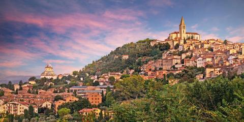 Hilltop cityscape at sunset with prominent church.