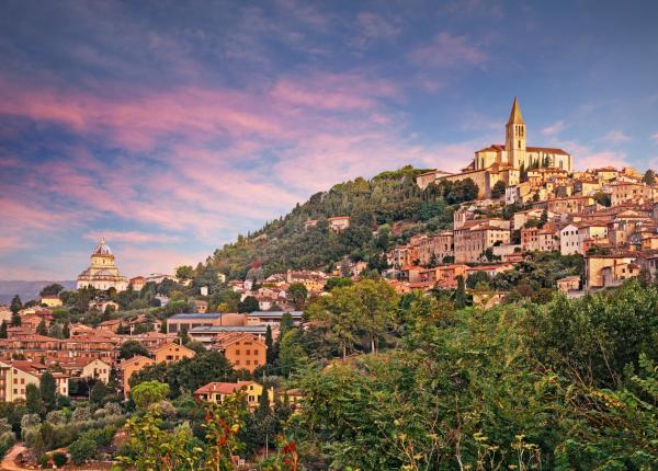 Hilltop cityscape at sunset with prominent church.