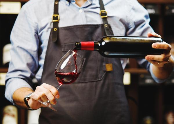 Sommelier pours red wine into a glass.